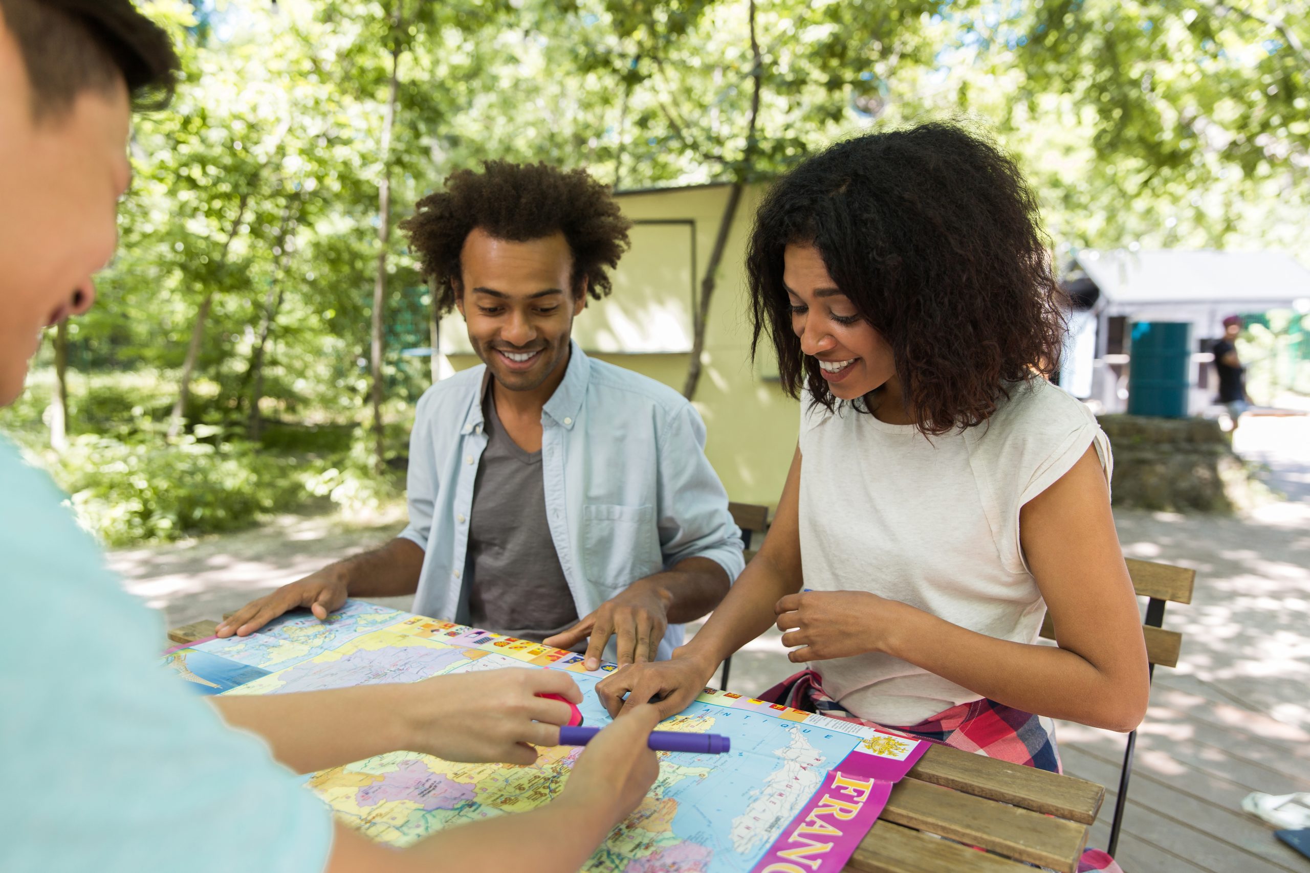 Image of concentrated young multiethnic friends students outdoors studying and talking with each other. Looking aside.